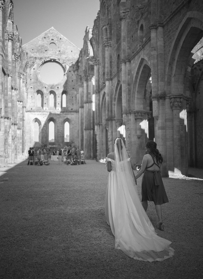 Bride walking down the aisle of roofless San Galgano Abbey for civil ceremony