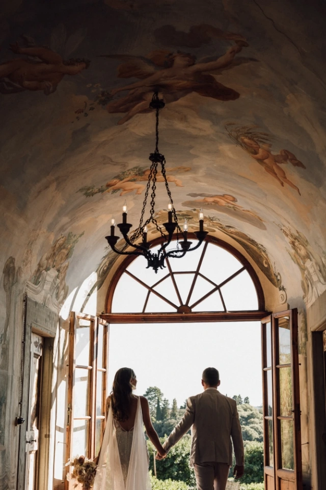 Bride and groom walk through the fescoed allway for their entrace at Villa Medicea di Liliano near Florence