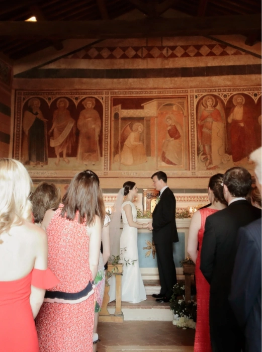 Bride and groom hold hands during intimate church ceremony in Tuscany