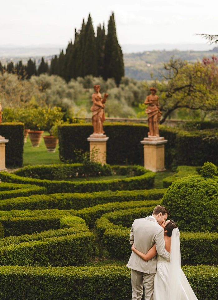 Bride and groom kiss in Italian garden of Villa di Catignano