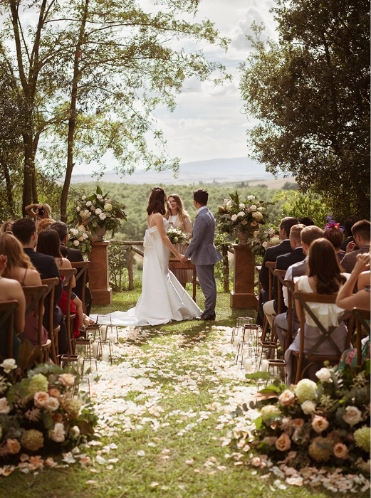 Bride and groom holding hands during symbolic ceremony in Tuscany countryside