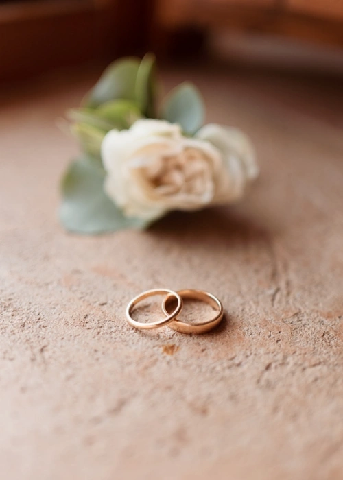 Detail of gold wedding bands with dusty pink flower