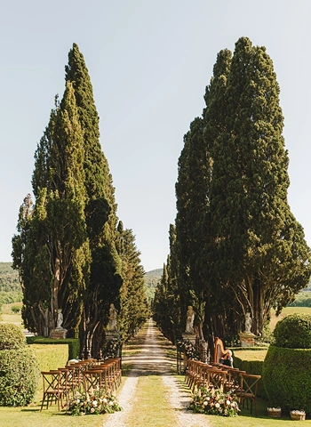 Ceremony setup in front of gate and cypress lined driveway of Borgo Stomennano