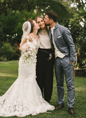 Bride and groom kiss Wedding planner Sara Barni on cheeks