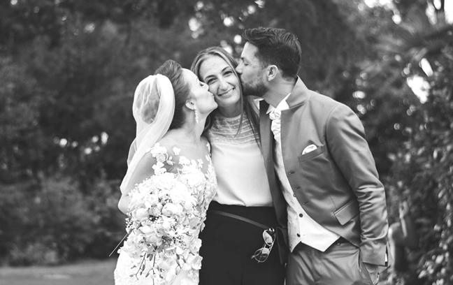 Wedding planner Sara Barni receives grateful kiss by bride and groom on the her cheeks