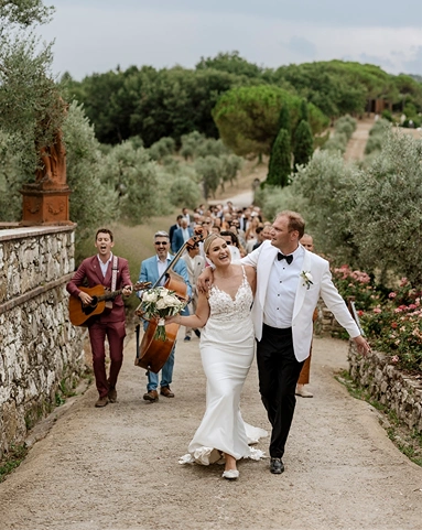Wedding day coordination service: bride and groom enjoy the music with guests while moving to dinner.