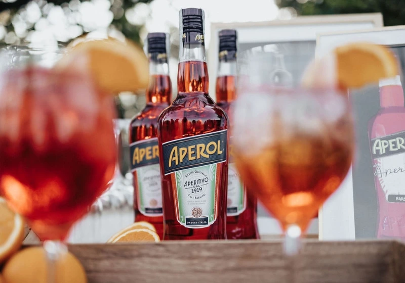 Detail shot of Aperol Spritz bottles with full glasses during orange, Aperol Spritz themed event
