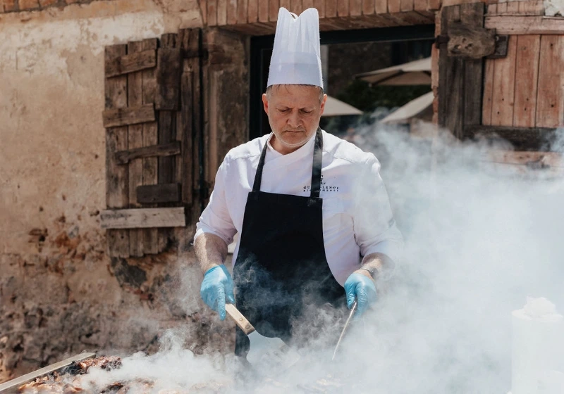 Chef cooking meats on smoky grill for BBQ linked event