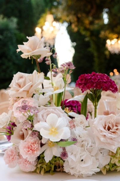 Close up of sculptureal wedding reception centerpiece featuring pink, purple, green and white flowers