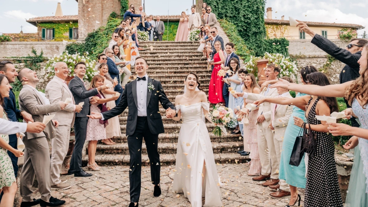 Bride and groom exit from the wedding ceremony with cheerful petal toss in front of stairs