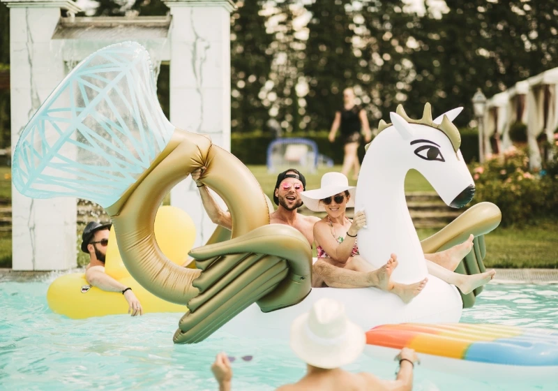 Newlyweds after the wedding day are enjoying a relaxing pool party with an engagement ring and unicorn pool floats