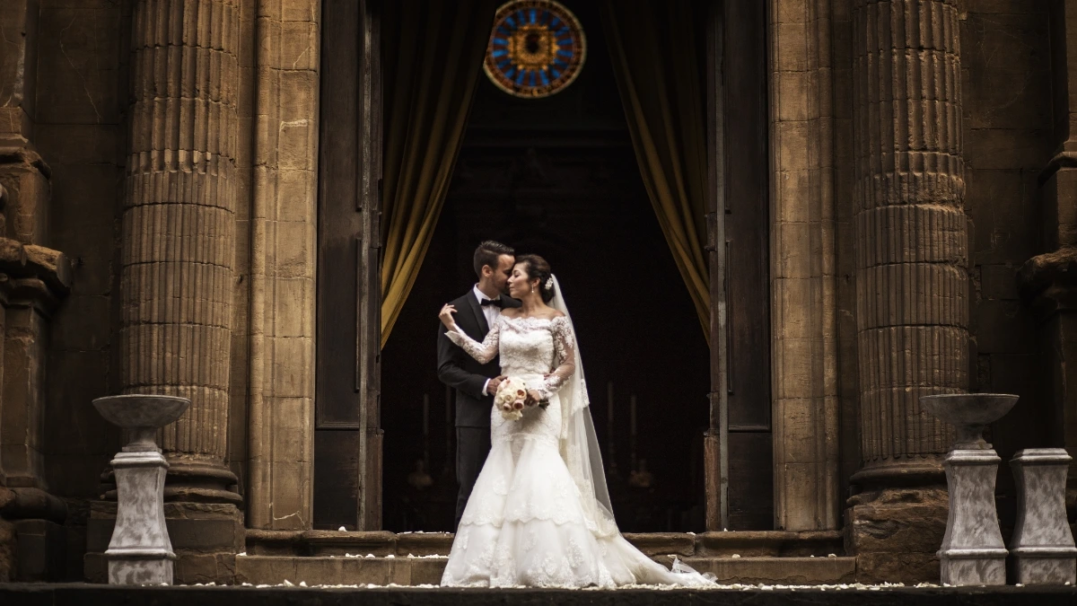Couple shot of bride and groom in front of church after religious wedding ceremony in Tuscany, Italy