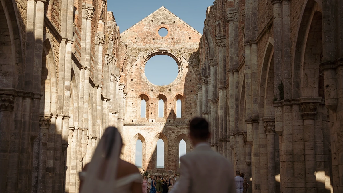 Bride and groom walk towards altar at San Galgano roofless abbey in Tuscany