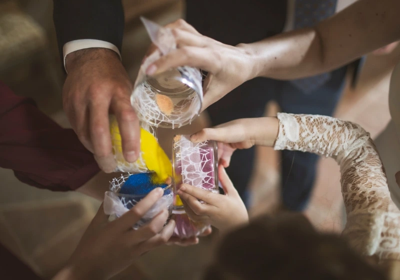 Bride, groom and daughters pour sand during sand ritual during symbolic wedding ceremony in Tuscany
