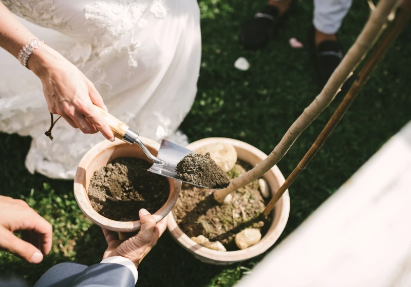 Bride and groom planting a tree during tree ceremony ritual in symbolic wedding in Tuscany