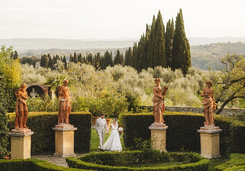 Bride and groom wonder around the Italian Garden of Villa Catignano framed by statues