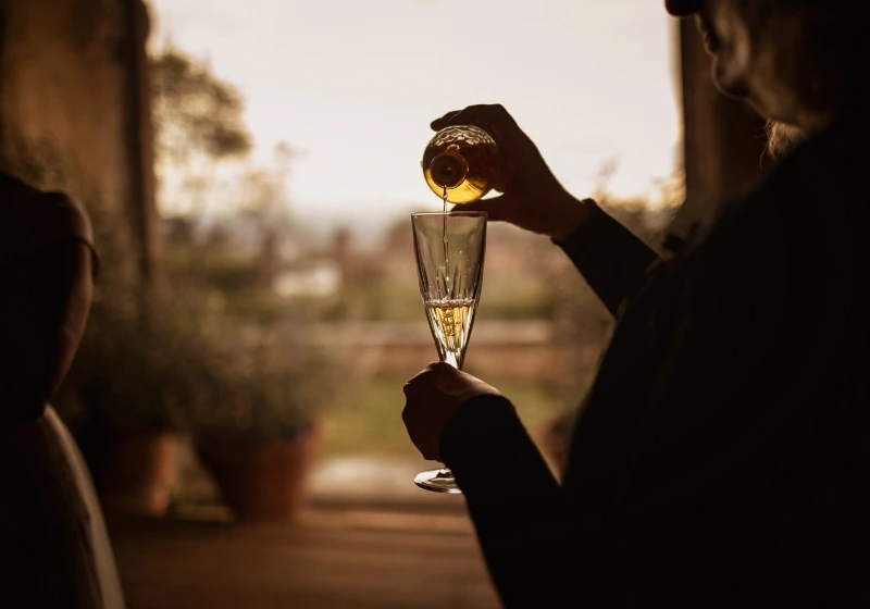 Groom pours wine in glass during wine box ritual during symbolic wedding ceremony in Tuscany