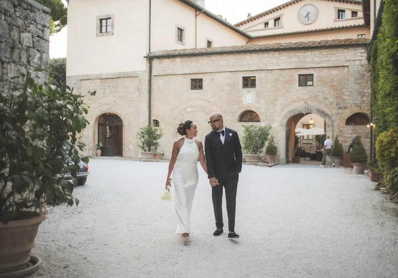 Photo of a bride and groom walking on a borgo pignano's street