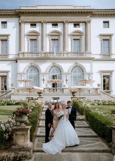 Photo of the bride and groom with two guest in front of the facade of villa cora