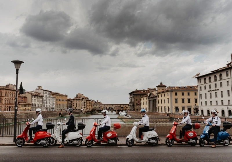 Funny photo of the groom and groomsman on withe and red vespas in Florence