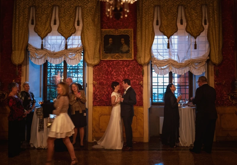 Photo of bride and groom with guest celebrating in a room of the venue 