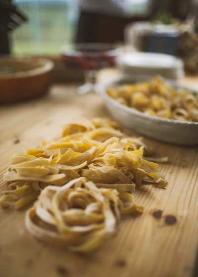 Fresh homemade tagliatelle pasta arranged on a rustic wooden table, 