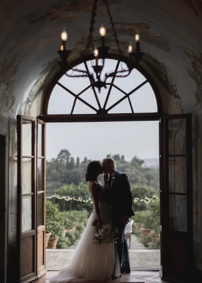 Newlyweds standing in front of the open glass doors of Villa Medicea di lilliano