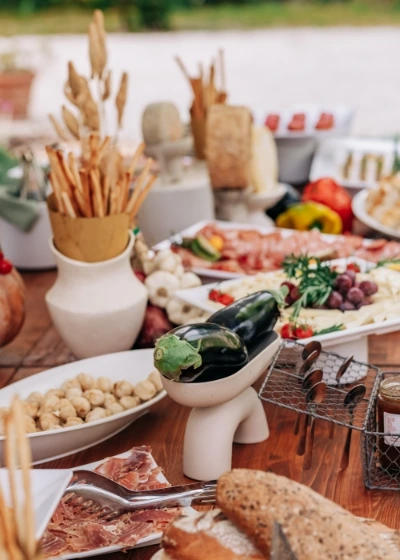 Rustic outdoor charcuterie board with cured meats, cheeses, fresh vegetables, breadsticks, and bread 